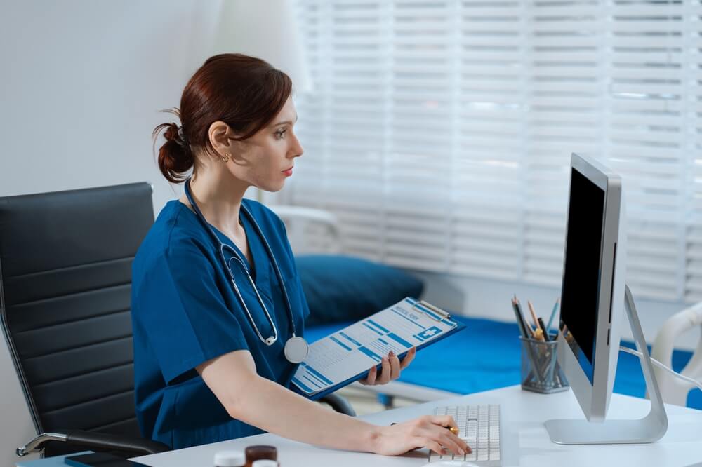 Medical billing specialist reviewing pain management insurance claims on computer